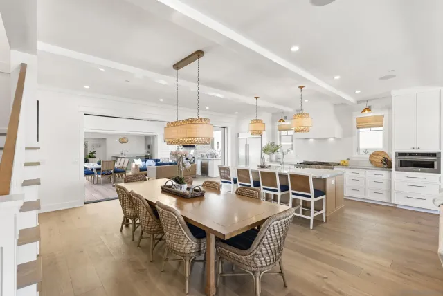 a view of a dining room and livingroom with furniture wooden floor a rug a flat screen tv a painting and a chandelier