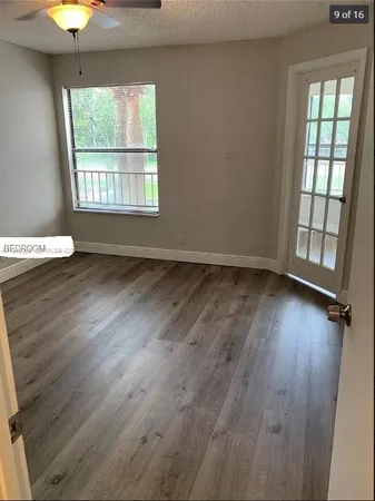 an empty room with wooden floor and windows