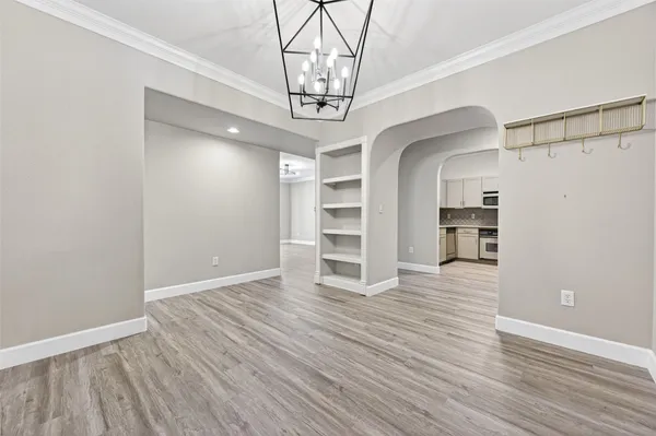 a view of a room with wooden floor chandelier and windows