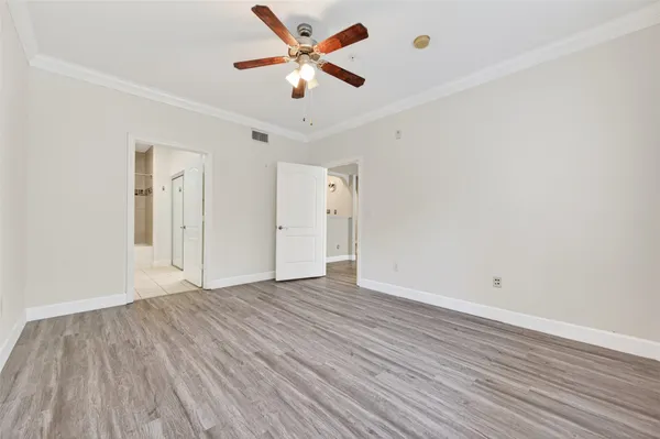 an empty room with wooden floor and ceiling fan