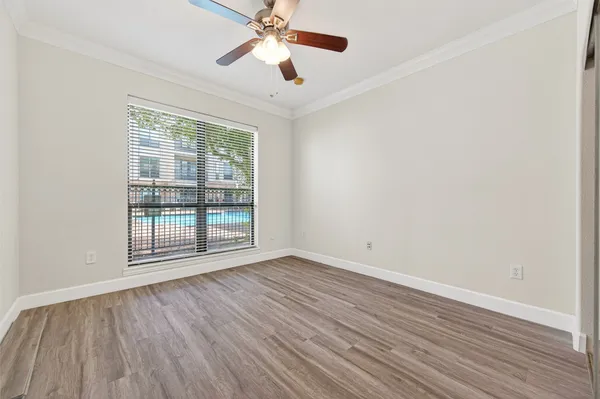 an empty room with wooden floor fan and windows