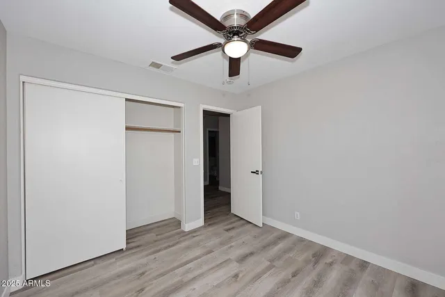 an empty room with wooden floor and a ceiling fan