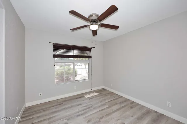 an empty room with ceiling fan and windows