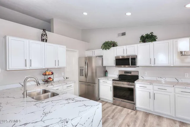 a kitchen with granite countertop a sink stainless steel appliances and white cabinets