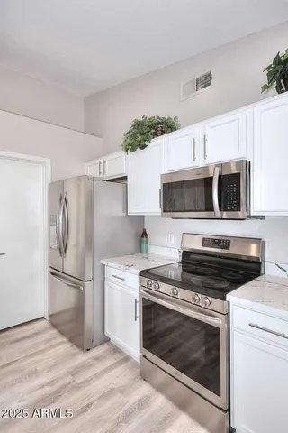 a kitchen with cabinets stainless steel appliances and wooden floor