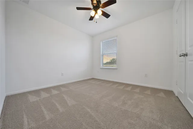 an empty room with a window and a ceiling fan