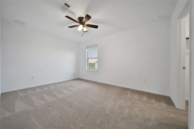 an empty room with a window and a fan