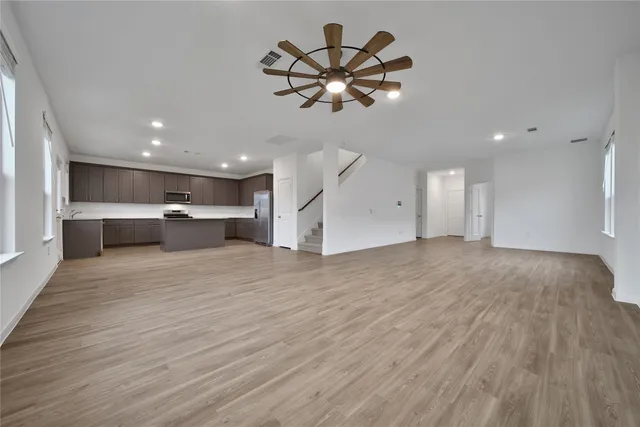 a view of empty room with wooden floor and ceiling fan