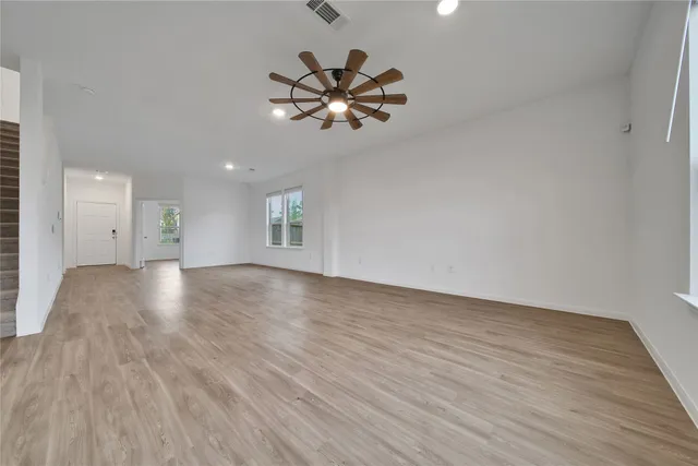 a view of an empty room with window and wooden floor