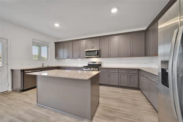 a kitchen with stainless steel appliances granite countertop a stove top oven a sink and dishwasher a refrigerator with wooden floors