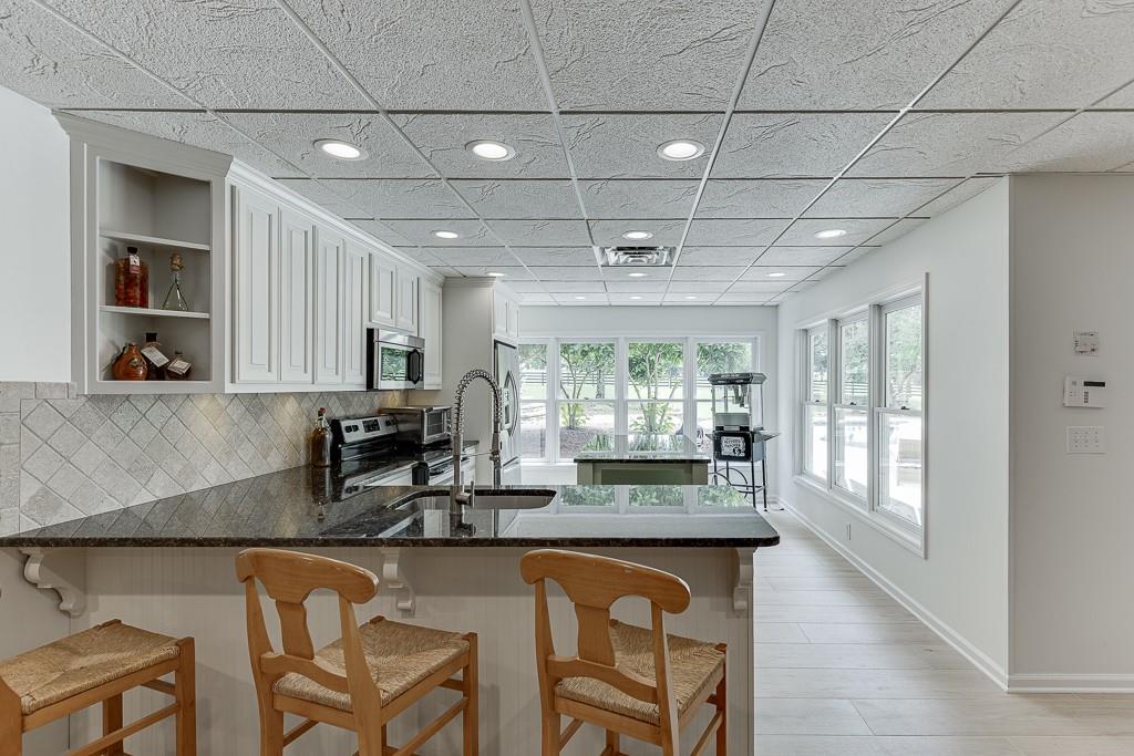 986 Austin Road Winder, GA 30680 - Photo 72 of 135 a kitchen with granite countertop a stove a sink a dining table and chairs with wooden floor