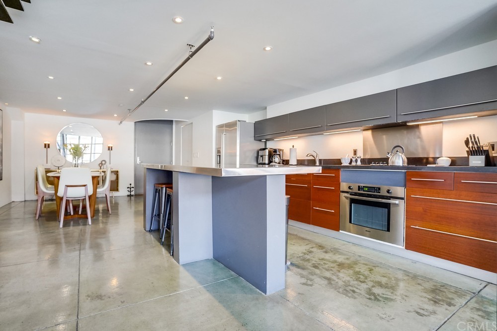 100 West 5th Street Long Beach, CA 90802 - Photo 22 of 53 a kitchen with stainless steel appliances granite countertop a stove top oven a sink dishwasher a dining table and chairs with wooden floor