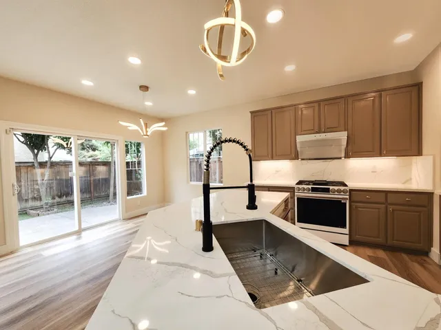 a kitchen with stainless steel appliances granite countertop a stove a sink and a microwave