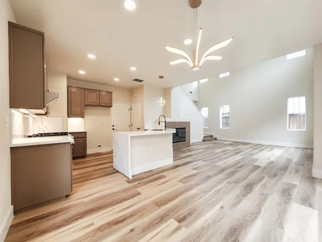 a large kitchen with kitchen island a sink dishwasher a stove and a refrigerator with wooden floor