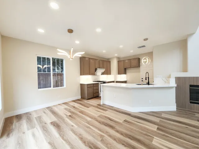 a large white kitchen with kitchen island a sink dishwasher and a stove with wooden floor
