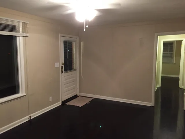 an empty room with wooden floor closet and windows