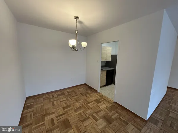 an empty room with kitchen view and wooden floor