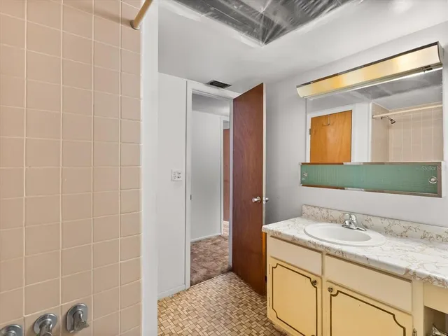 a bathroom with a granite countertop sink a mirror and a shower