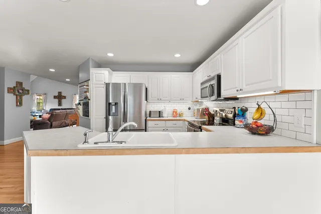 a kitchen with kitchen island granite countertop stainless steel appliances refrigerator cabinets dining table and chairs