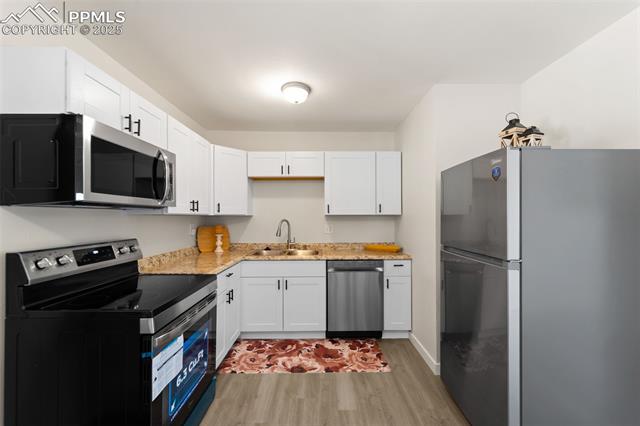 1663 Maxwell Street Colorado Springs, CO 80906 - Photo 10 of 23 Kitchen with stainless steel appliances, white cabinetry, and light wood-style flooring