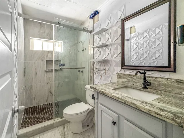 a bathroom with a granite countertop sink a toilet and a shower