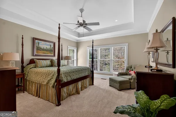a spacious bedroom with a bed couch chandelier and a window
