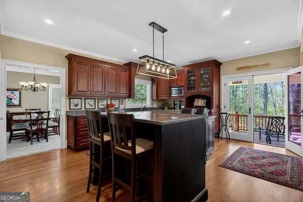 a kitchen with stainless steel appliances granite countertop a stove a refrigerator a sink a dining table and chairs with wooden floor