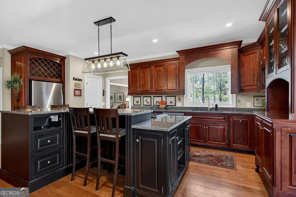 a kitchen with stainless steel appliances granite countertop a stove a sink dishwasher and a refrigerator with wooden cabinets