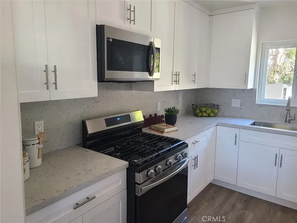 a kitchen with stainless steel appliances granite countertop white cabinets and a stove top oven