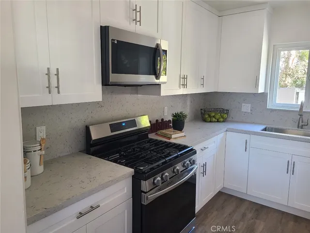 a kitchen with stainless steel appliances granite countertop white cabinets and a stove top oven