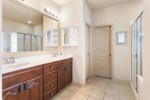 a spacious bathroom with a double vanity sink a mirror and a shower