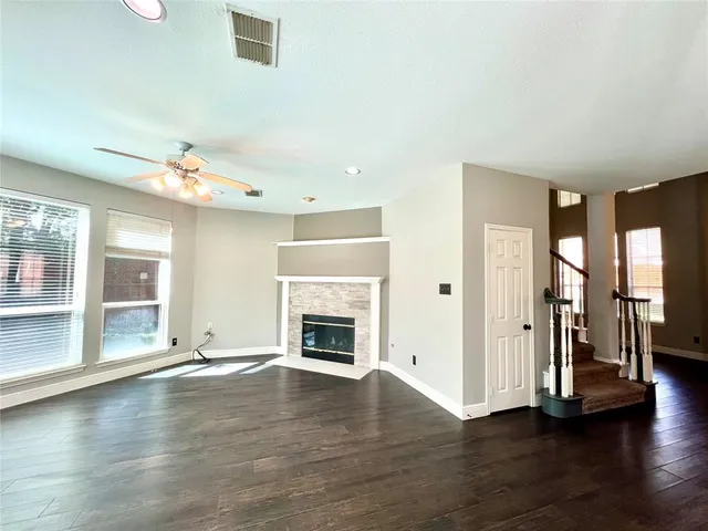 an empty room with wooden floor fireplace and windows