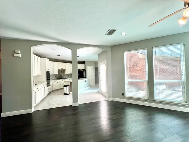 an empty room with wooden floor and windows