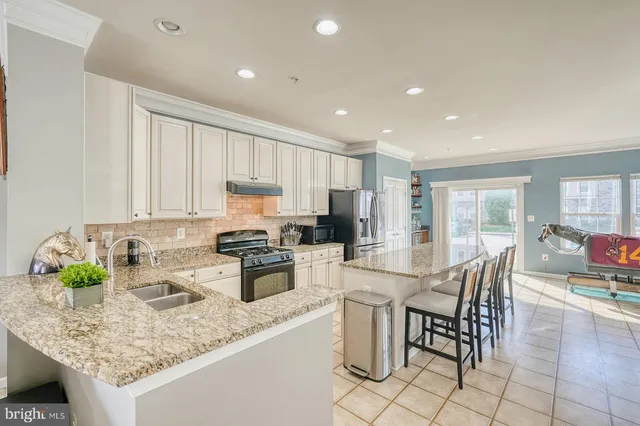 a kitchen with stainless steel appliances granite countertop a table chairs sink refrigerator and cabinets