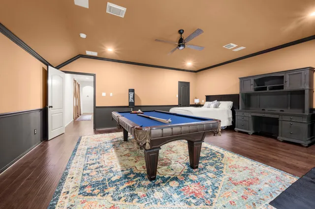 a room with pool table a flat screen tv and kitchen view