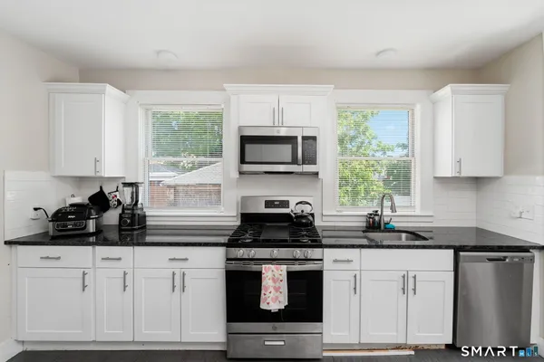 a kitchen with white cabinets and black appliances