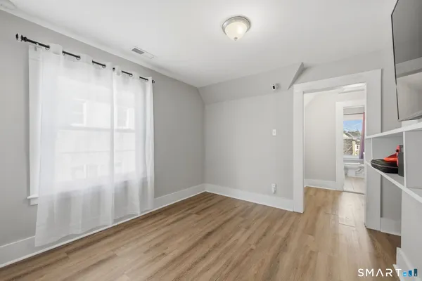 a view of empty room with wooden floor and fan