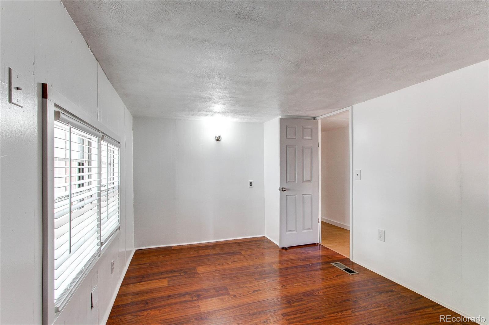 1015 Mac Davidson Circle Dacono, CO 80514 - Photo 15 of 22 a view of an empty room with wooden floor and a window