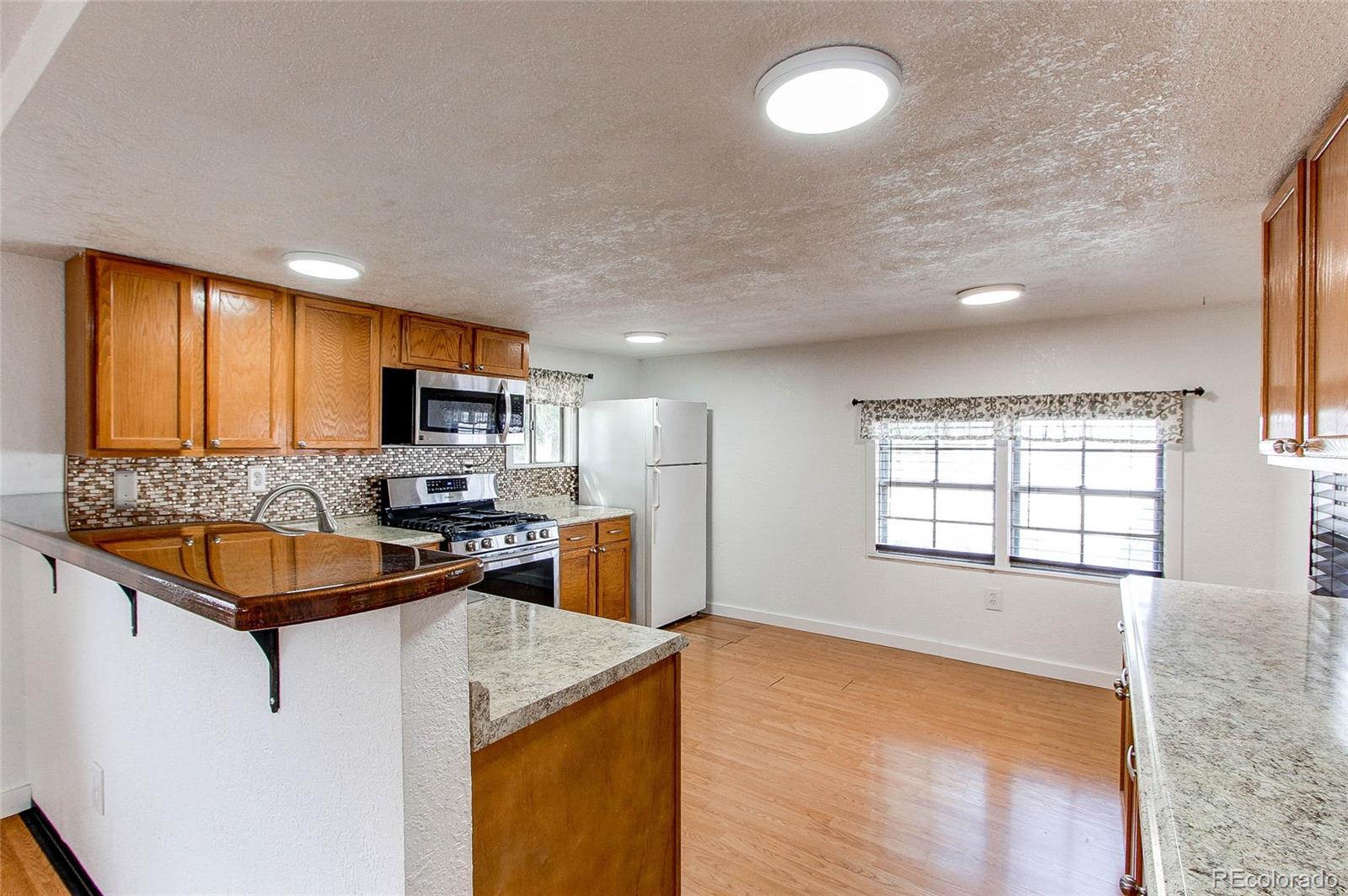 1015 Mac Davidson Circle Dacono, CO 80514 - Photo 5 of 22 a kitchen with stainless steel appliances granite countertop a sink stove and refrigerator