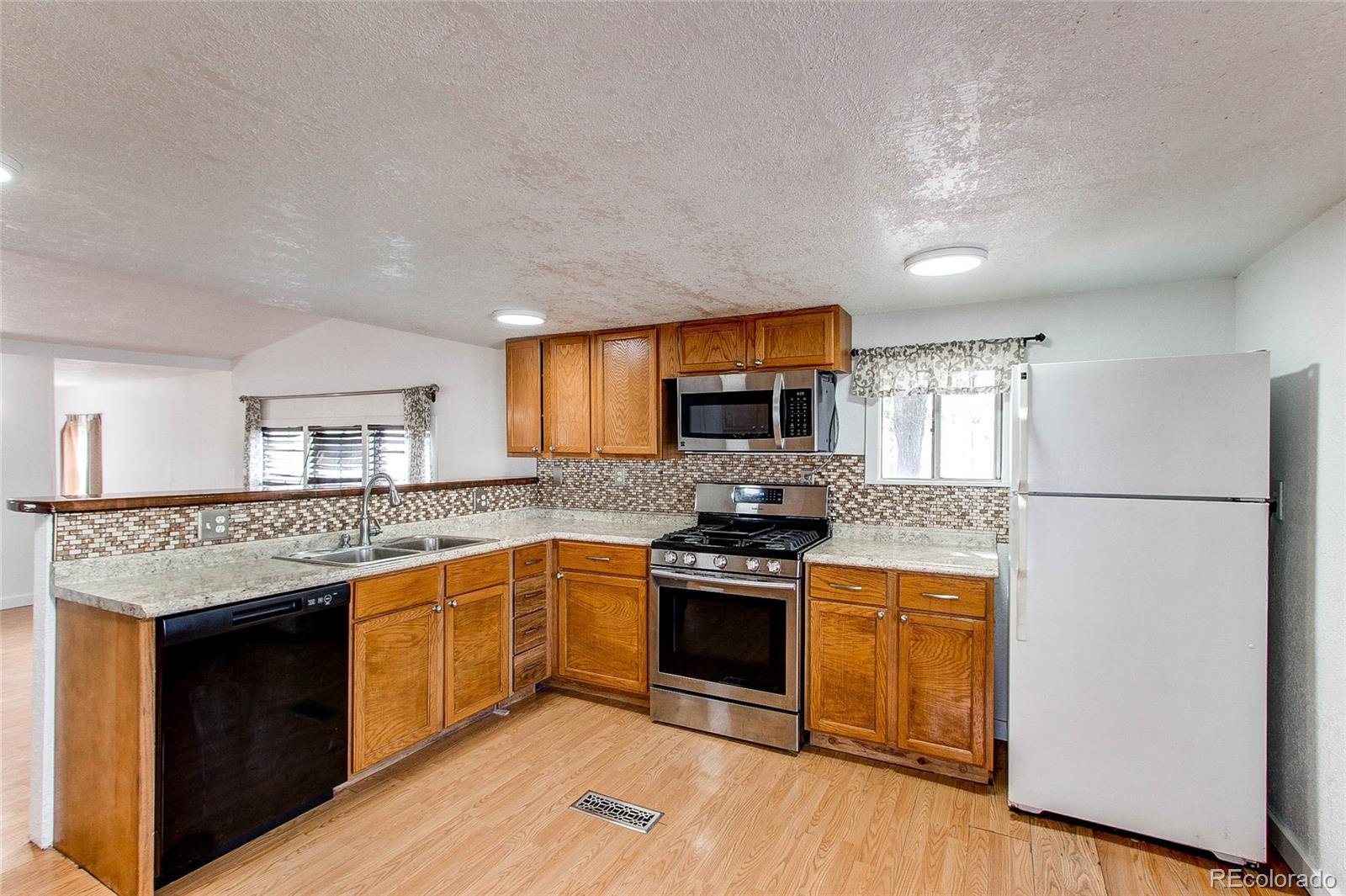 1015 Mac Davidson Circle Dacono, CO 80514 - Photo 6 of 22 a kitchen with stainless steel appliances granite countertop a stove top oven and sink
