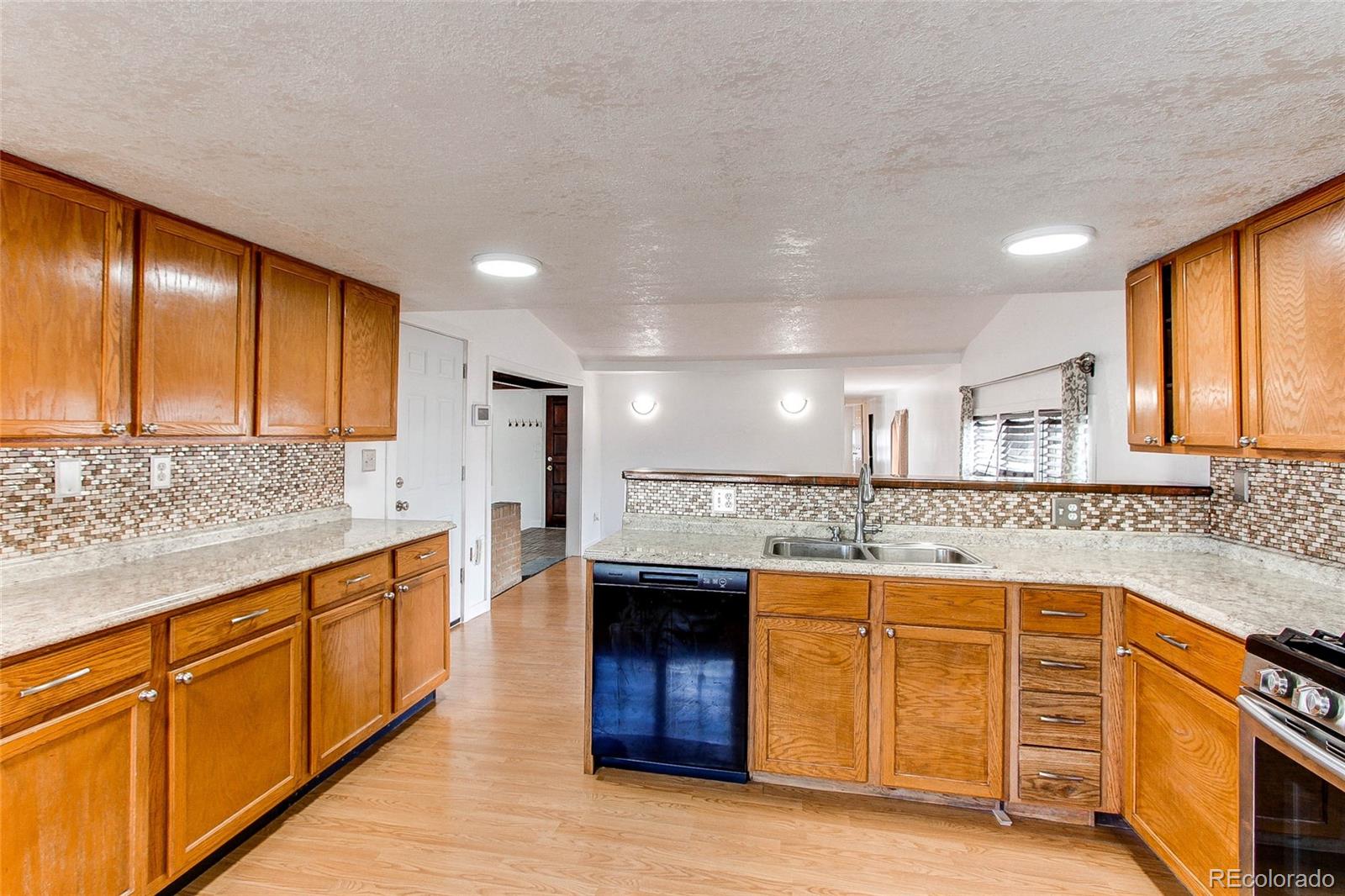 1015 Mac Davidson Circle Dacono, CO 80514 - Photo 7 of 22 a kitchen with stainless steel appliances granite countertop a sink and cabinets