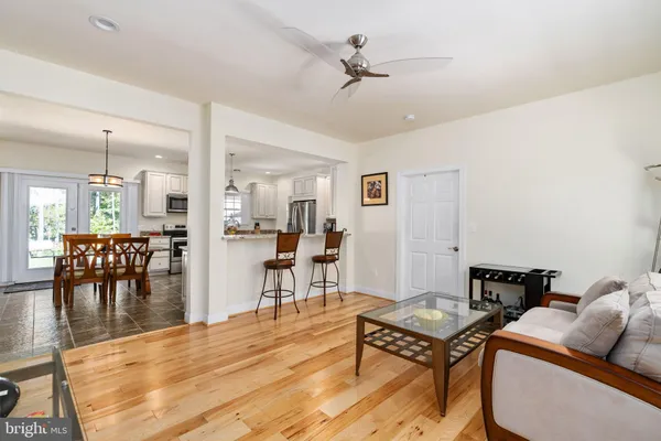 a living room with furniture and a dining table with wooden floor