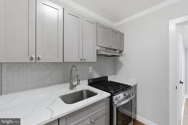 a kitchen with granite countertop a sink a stove and cabinets