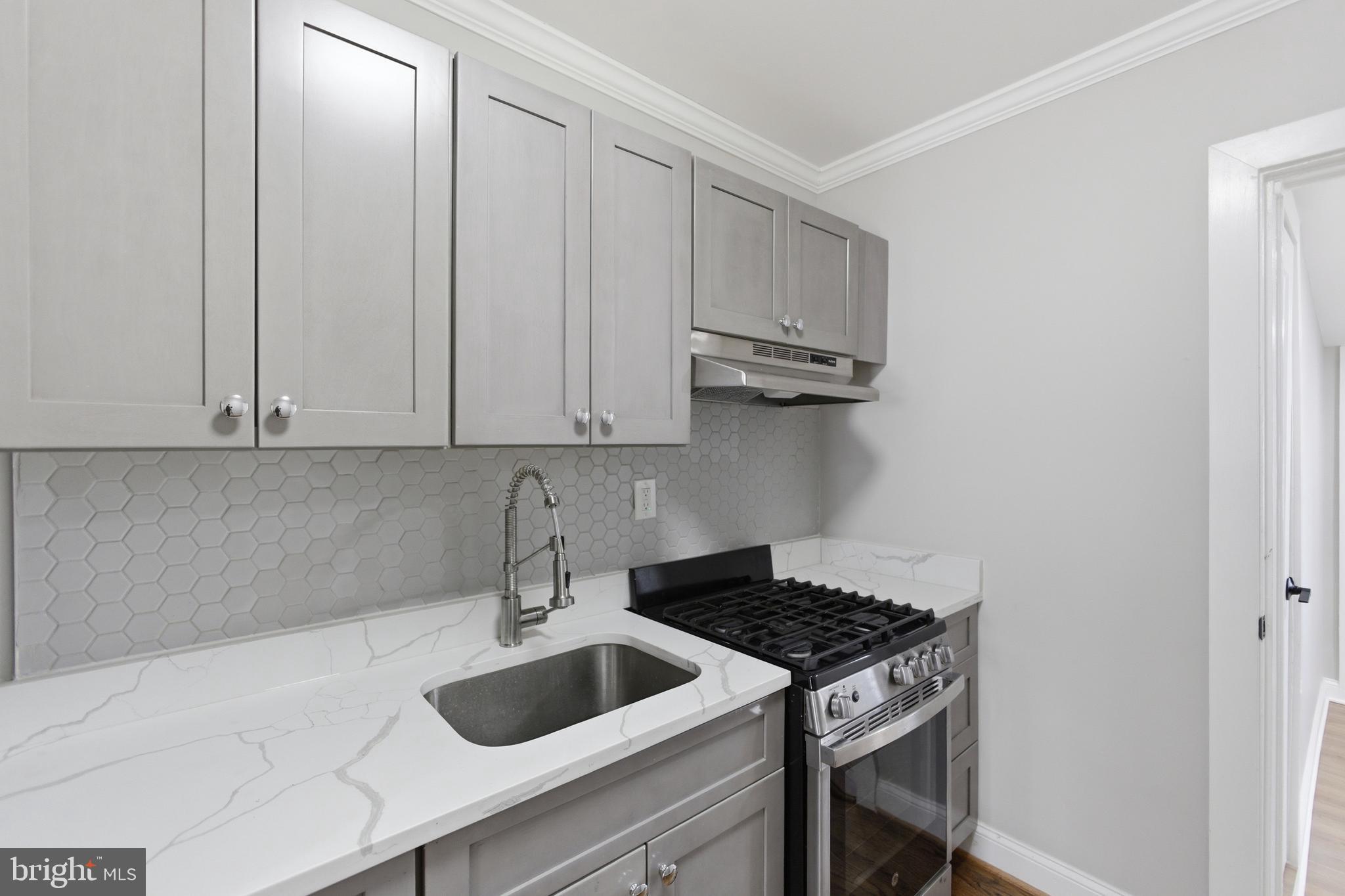 1250 Holbrook Terrace Northeast, Unit 3 Washington, DC 20002 - Photo 9 of 12 a kitchen with granite countertop a sink a stove and cabinets