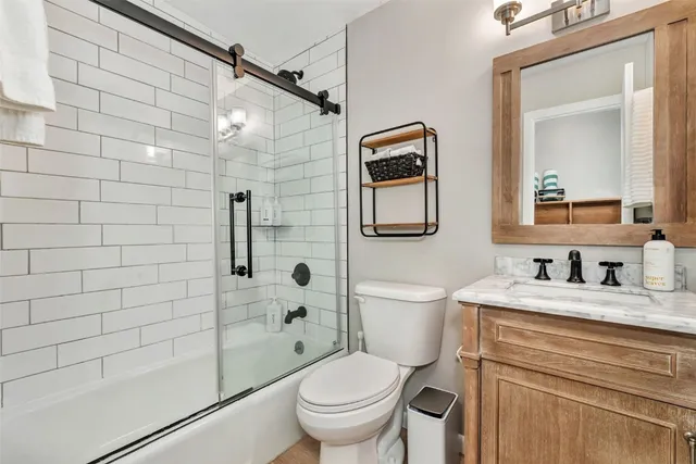 a bathroom with a granite countertop toilet sink shower and mirror