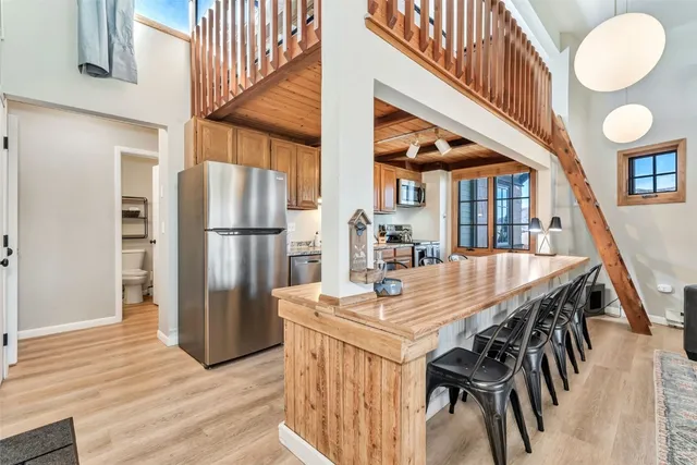 a kitchen with stainless steel appliances granite countertop a dining table chairs and entryway