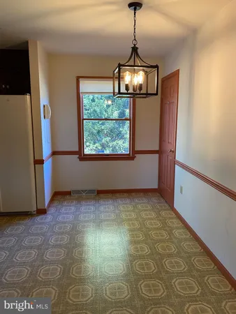 a view of an empty room with window and chandelier