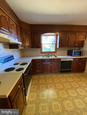 a kitchen with stainless steel appliances a stove a microwave a sink and cabinets