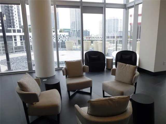a living room with furniture a flat screen tv and a floor to ceiling window