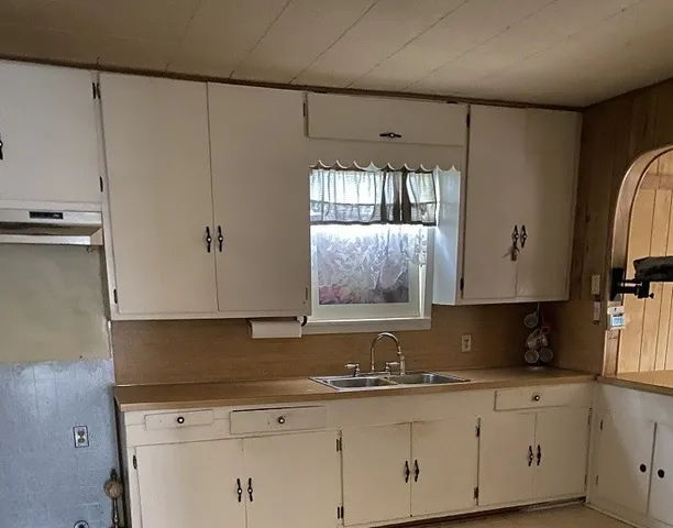 a kitchen with granite countertop white cabinets and sink